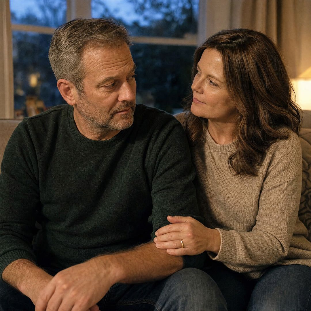 A couple in their 50s on the sofa, her hand on his arm